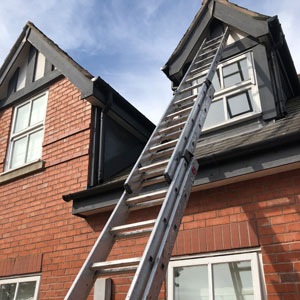 Painter and decorator using ladders outside semi-detatched house